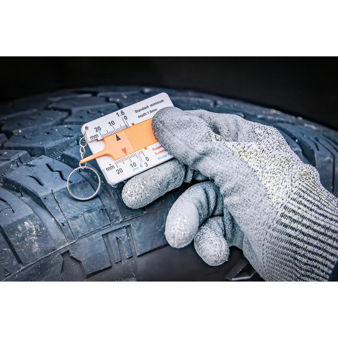 Bild der Nutzung eines Profiltiefenmessers am Reifen eines Fahrzeugs mit Blick auf die Skala und das Messergebnis