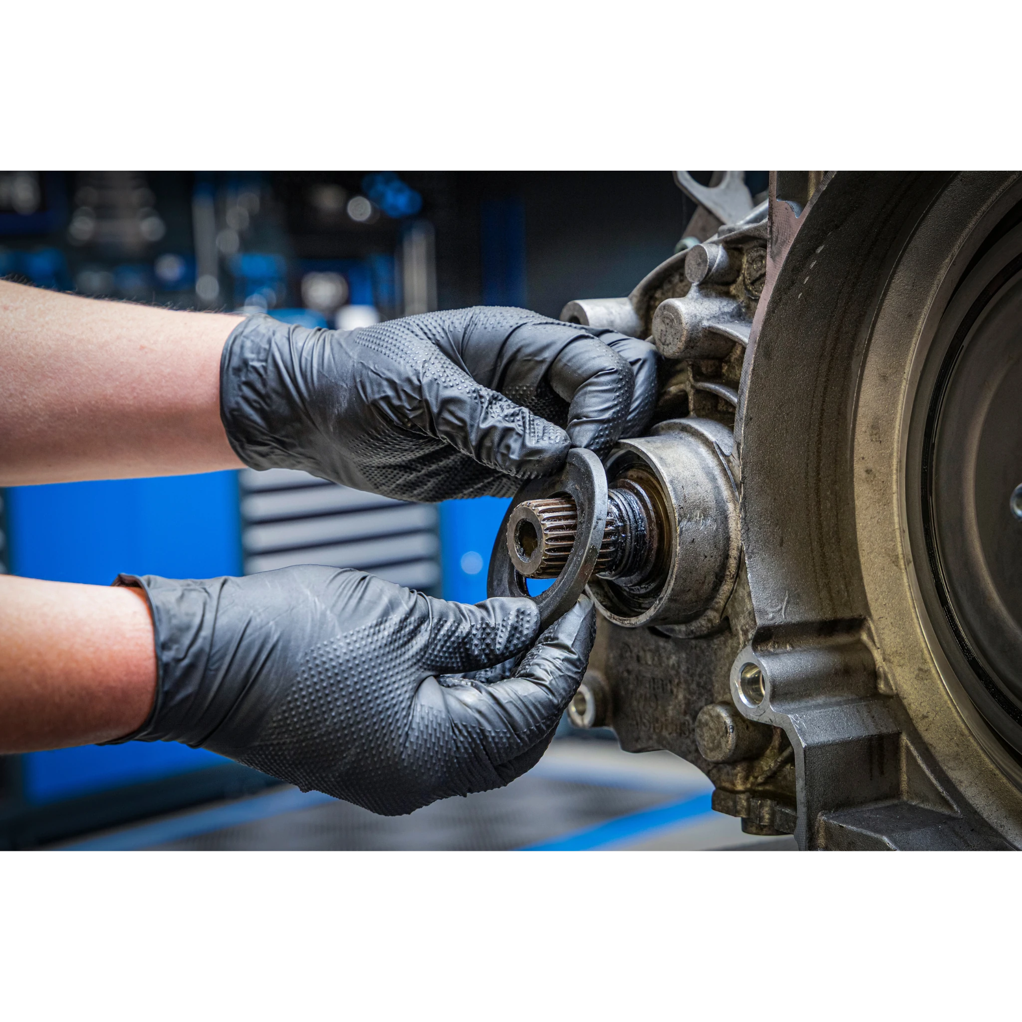 Bild der Nutzung von Einweghandschuhen an einem ausgebauten Motor in der Kfz-Werkstatt bei der Arbeit an einem Simmerring
