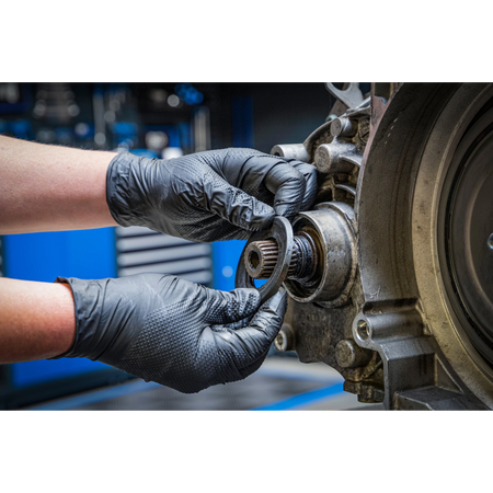 Bild der Nutzung von Einweghandschuhen an einem ausgebauten Motor in der Kfz-Werkstatt bei der Arbeit an einem Simmerring
